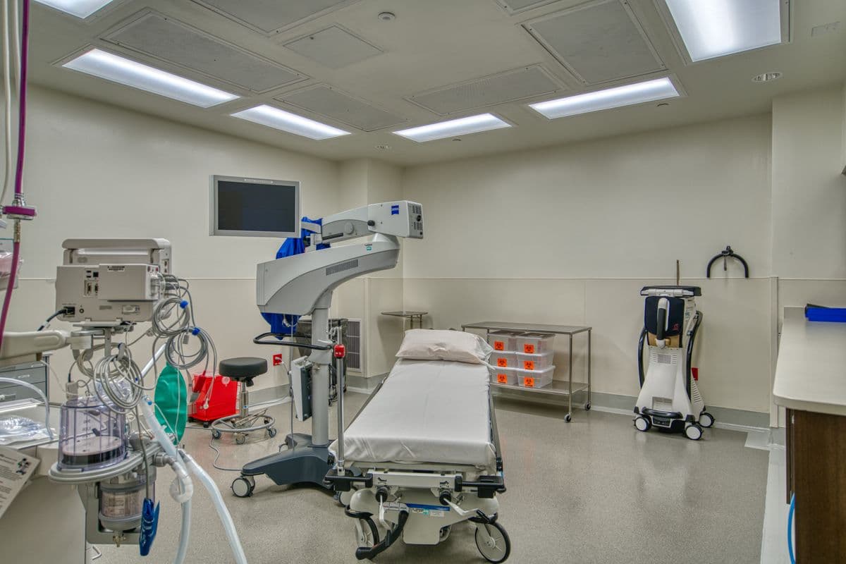 A procedure room with a surgical microscope and monitors